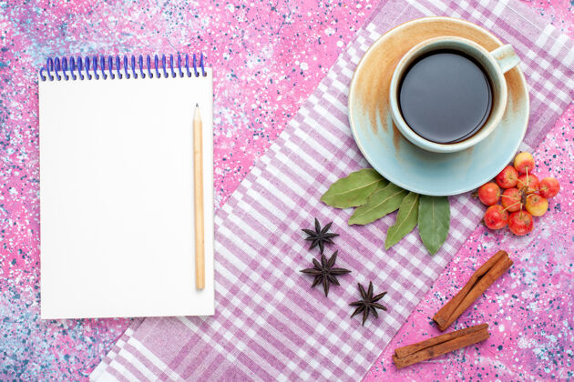 记事本顶视图一杯茶 肉桂笔记本和樱桃放在粉红色的背景上 茶喝水果色的茶碟肉桂杯子