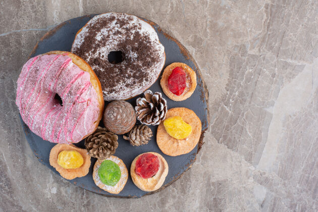 美味把松果 甜甜圈和饼干放在大理石板上视图美味糕点