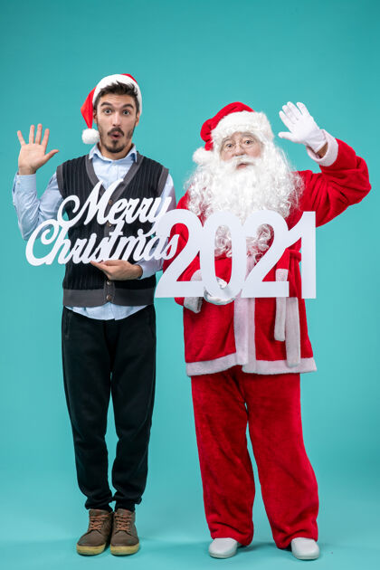年前视图圣诞老人与年轻的男性举行圣诞快乐和蓝色地板上的文字颜色雪新年假期圣诞节圣诞老人视图男人