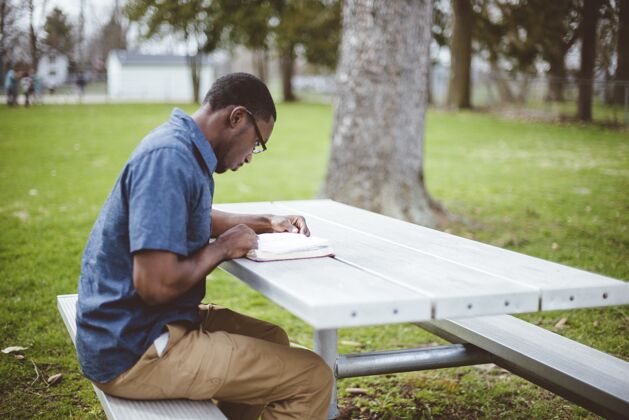 男性坐在桌子旁读圣经的非裔美国男性非裔灵性宗教