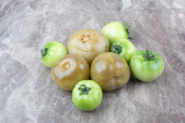 未熟的新鲜的绿色西红柿和腌制西红柿放在大理石表面天然番茄蔬菜