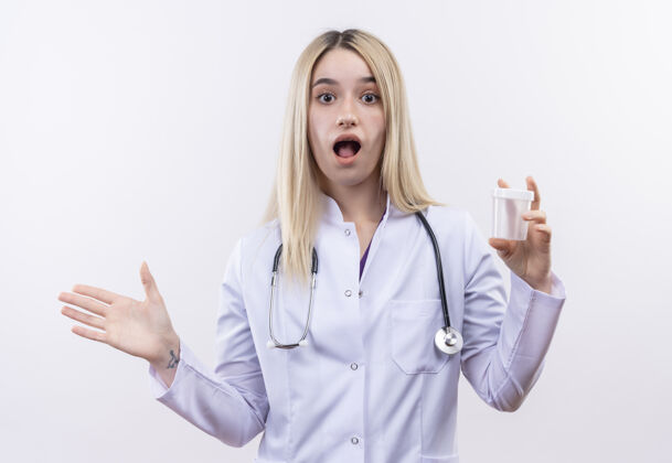 医生惊讶的医生年轻的金发女孩戴听诊器和医疗长袍举行空可以举起手孤立的白色背景听诊器手长袍