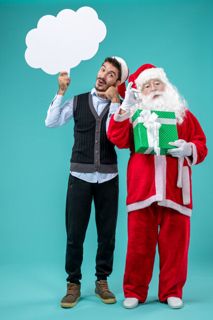 成人前视图圣诞老人和年轻的男性谁持有白色云标志的蓝色背景云持有圣诞老人