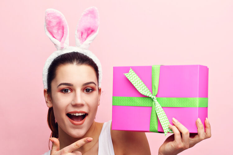 节日戴着兔子耳朵拿着礼物的快乐的年轻女人传统美丽象征