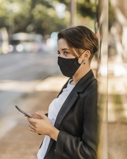 女人戴着医用面罩的女人在检查她的手机面具街道美丽