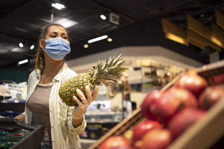 疾病戴着卫生口罩 橡胶手套和购物车的妇女在杂货店购买日冕病毒期间的水果 准备进行大流行隔离传染性大流行女人