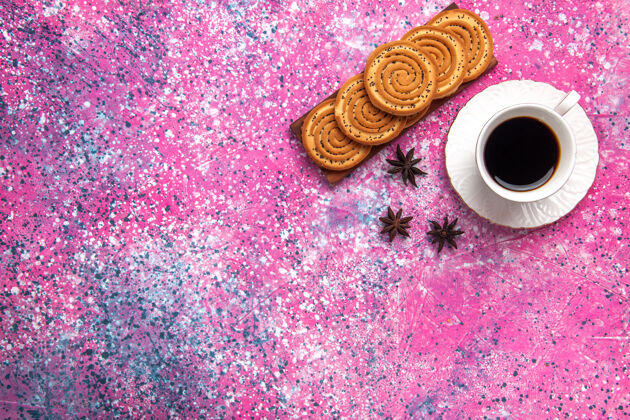 杯子浅粉色的桌子上放着一杯茶和饼干红茶饼干饮料