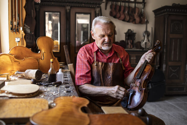 工作高级木匠在他的木匠工作室里打磨小提琴乐器手工抛光压花