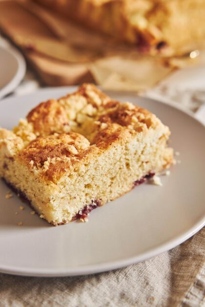 可口特写镜头的一块美味的杰里面包屑床单蛋糕在白色的木桌上蛋糕甜点糖果