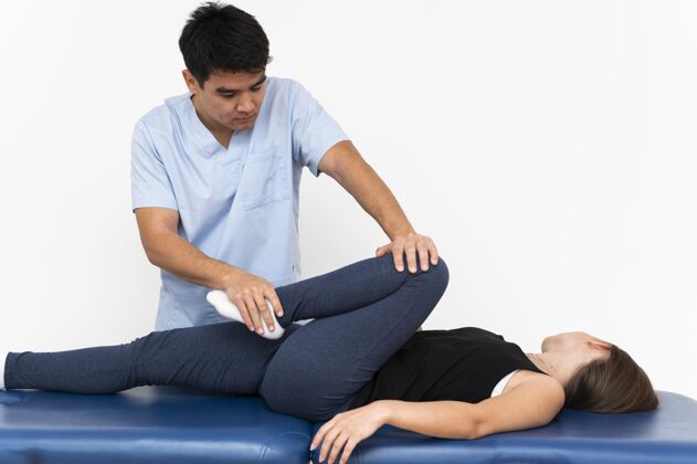 理疗师理疗师和女病人做腿部运动移动女性复制