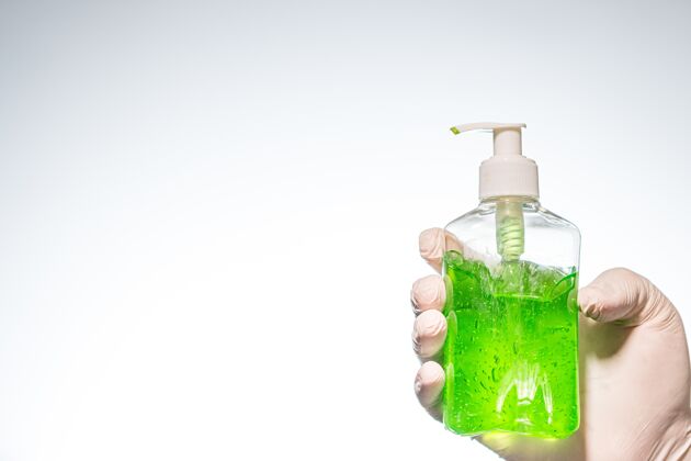 消毒特写镜头：一个人戴着乳胶手套 在灯光下拿着绿色洗手液手套凝胶卫生