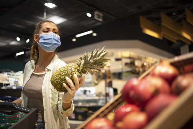 疾病戴着卫生口罩 橡胶手套和购物车的妇女在杂货店购买日冕病毒期间的水果 准备进行大流行隔离传染性大流行女人