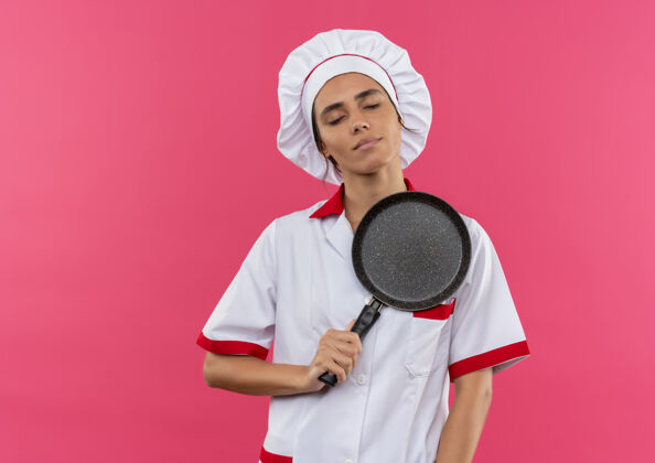厨师年轻的女厨师闭上眼睛 穿着厨师制服 把煎锅放在心上 留着空间厨师放平底锅