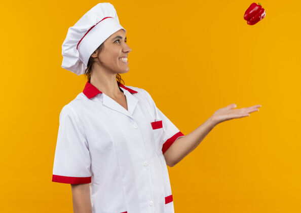 厨师站在侧视图微笑着年轻的女厨师穿着厨师制服扔西红柿与复制空间女穿着制服