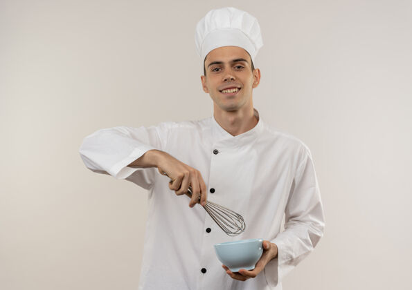 男面带微笑的年轻男厨师穿着厨师制服拿着面团和碗拂着拿着制服