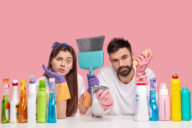 女不高兴的白人妇女和男子不悦地看着 感到疲劳后 春季打扫房子 使用扫帚家庭主妇丈夫家务