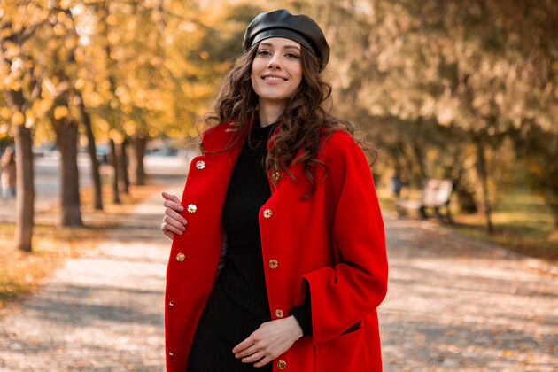 户外迷人的时尚微笑的女人卷发漫步在公园穿着温暖的红色外套秋季时尚 街头风格 戴贝雷帽装束摆姿势连衣裙