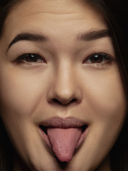 积极年轻而感性的中国女人的特写肖像女性模特的高细节照片 保持良好的皮肤和明亮的面部表情人类情感的概念伸出舌头 俏皮亲密明亮详细