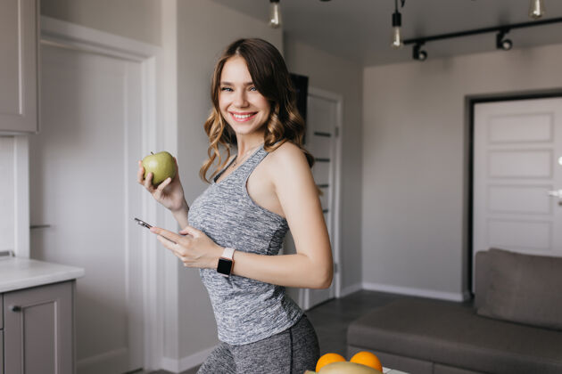 积极一个穿着灰色服装的快乐女人 表达着快乐漂亮女孩手里拿着苹果的室内照片苹果吃休息