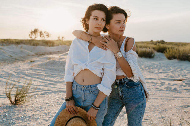 伴侣可爱的两个年轻女子在日落海滩上玩得很开心 男女同性恋的爱情浪漫同性恋约会在一起