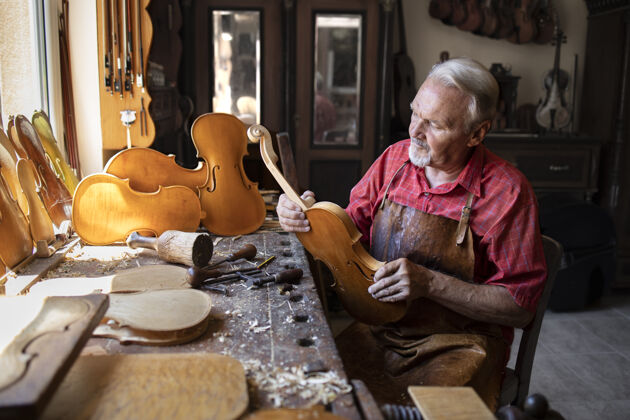 工匠高级木匠在他的木匠车间组装小提琴乐器的零件木制品锤子技能
