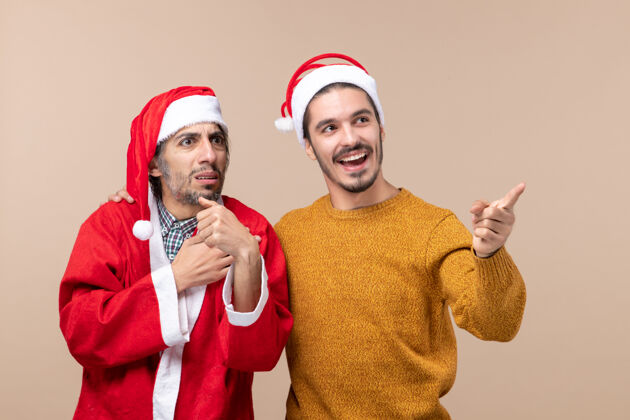 米色前视图两个圣诞节男子都在看米色孤立背景的权利帽子圣诞节两个