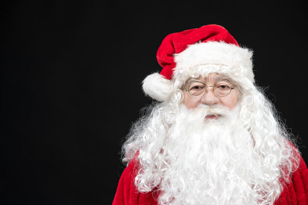 圣诞圣诞老人穿着经典的红色套装 留着白胡子 站在黑色的墙上冷快乐老人