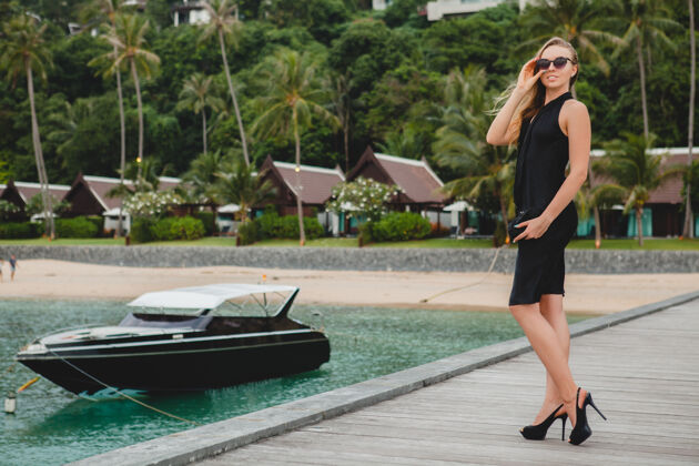 海洋奢华性感迷人的女人穿着黑色礼服在豪华度假酒店的码头上摆造型 戴着墨镜 暑假 热带海滩豪华女性天堂