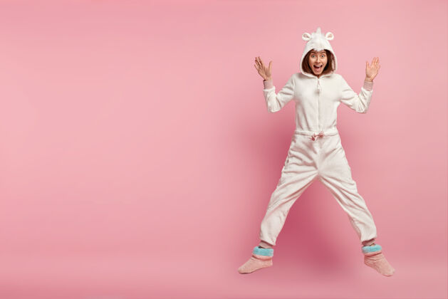 睡衣室内拍摄喜出望外的快乐女孩穿着舒适的国内小泉服装 跃过粉色空间手舒适欧洲