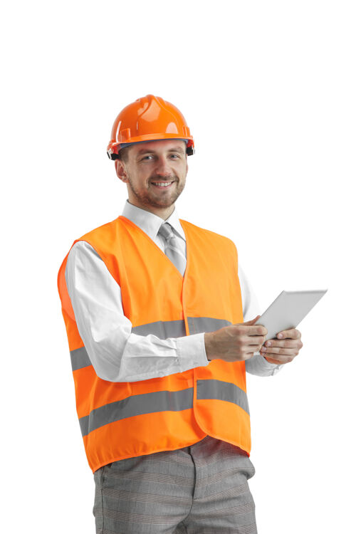 小工具一个穿着建筑背心 戴着带石碑的橙色头盔的建筑工人头盔现场专业