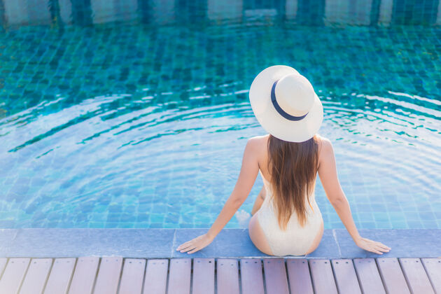 身体美丽的亚洲年轻女子在度假酒店的室外游泳池周围放松的肖像热带游泳享受