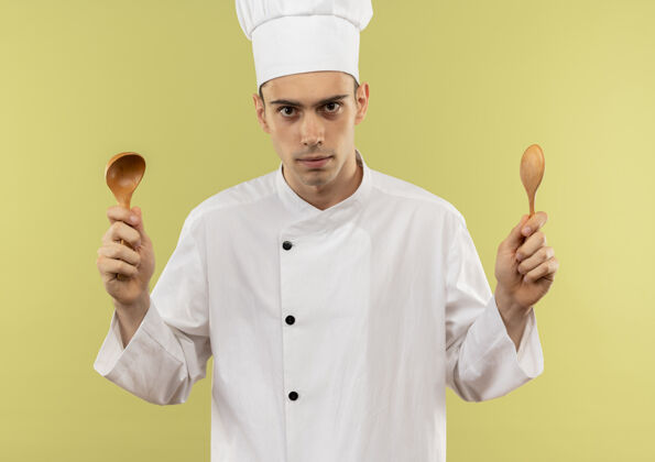 厨师年轻的男厨师穿着厨师制服 拿着勺子站在隔离的绿墙上年轻勺子拿着