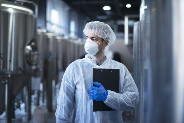 操作员穿着白色防护服 戴着发网和口罩的技术员站在食品厂里实验室防护浓度