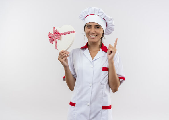 点面带微笑的年轻女厨师穿着厨师制服手持心形盒子 指着上面的复印空间女心制服