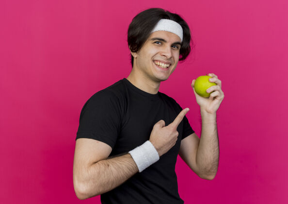 苹果穿着运动服 头戴绿帽子的年轻人用食指指着苹果运动男士粉色