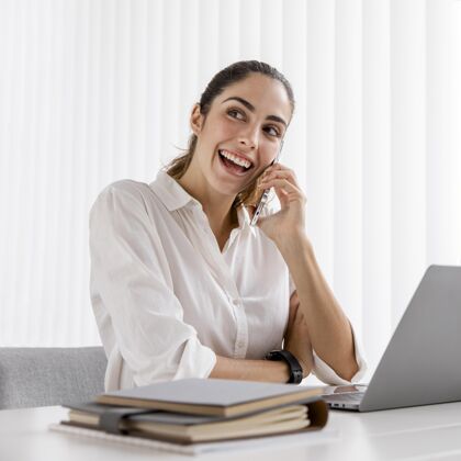 专业人士smileybusinesswoman使用智能手机和笔记本电脑的前视图女性优雅个性