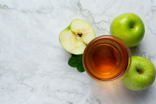 玻璃杯一杯青苹果保健茶放在新鲜青苹果旁边鸡尾酒草药饮料