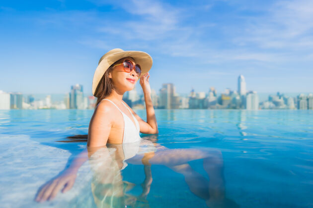 摩天大楼美丽的亚洲年轻女子在户外游泳池周围放松 城市景色尽收眼底享受城市度假村