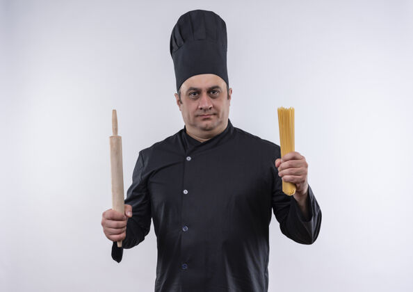看身着厨师制服的中年男厨师手拿擀面杖和意大利面站在隔离的白色墙上厨师意大利面别针