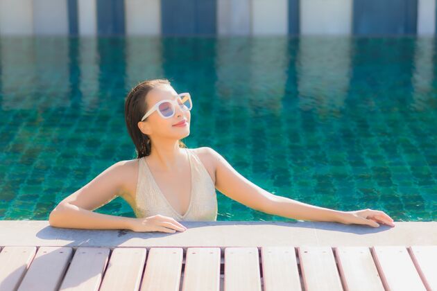 休闲美丽的亚洲年轻女子在度假酒店的室外游泳池周围放松的肖像游泳游泳泳装