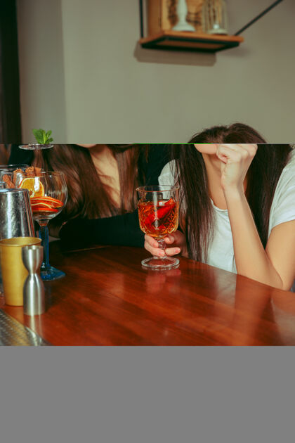 酒女朋友在酒吧喝酒她们坐在一张有鸡尾酒的木桌旁水果酒吧年轻