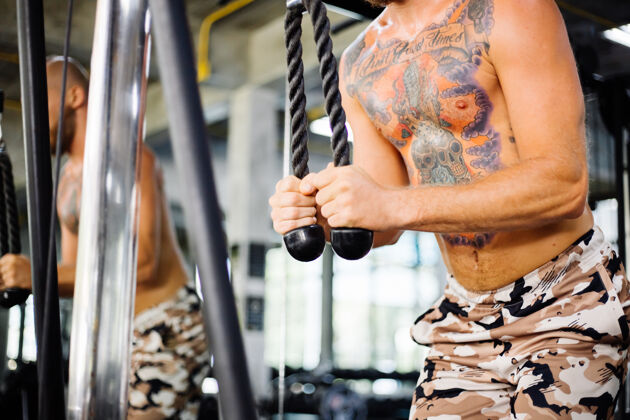 人纹身的健康男人在健身房锻炼肌肉年轻赤裸上身