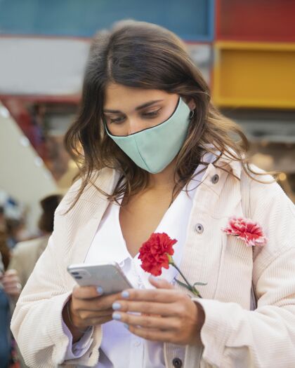 冠状病毒拿着花用智能手机的女人流行病疾病疾病