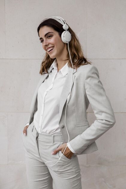企业家优雅的女商人在耳机上听音乐的前视图行政人员音乐个人