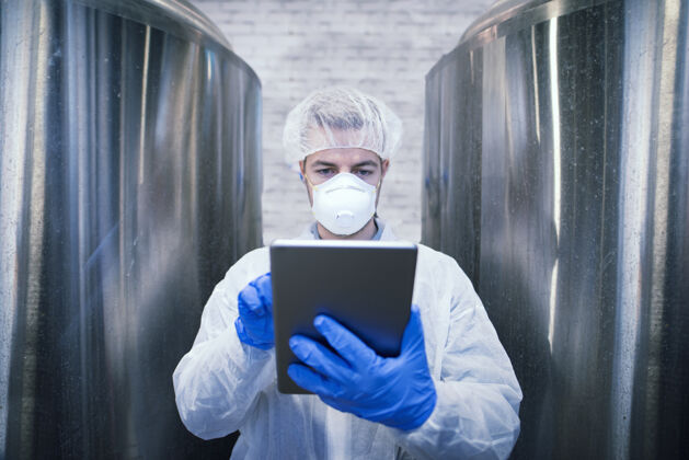 实验室身着白色防护服的工艺师画像食品生产厂手持平板电脑工作场所服装专家