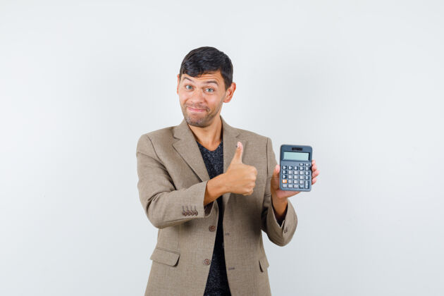 抱着年轻的男性手持计算器 穿着灰褐色夹克 黑色衬衫 露出大拇指 看上去很高兴 正对着前方灰色人表情