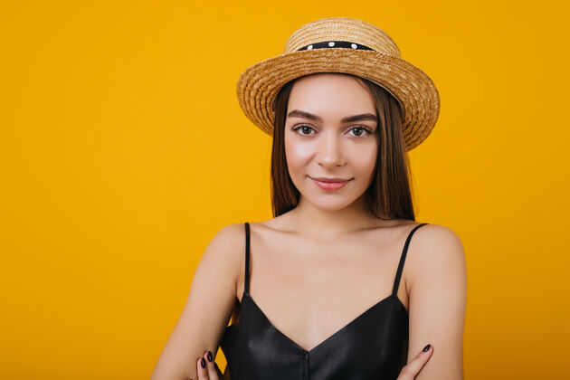 优雅棕色大眼睛的时髦年轻女子摆出温柔微笑的姿势漂亮的欧洲女孩的室内画像戴着时髦的草帽橙色有趣微笑