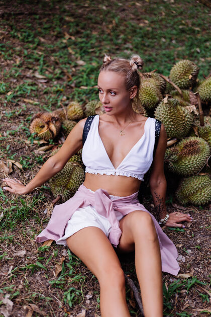 背包热带田野上的年轻时尚女士 带着榴莲水果皮肤肖像度假