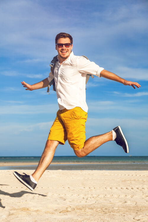 男孩时尚户外写真帅哥穿着鲜艳的时尚休闲装漫步在热带海滩背包客人天空