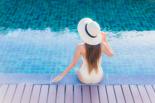 休闲美丽的亚洲年轻女子在度假酒店的室外游泳池周围放松的肖像水疗休息身体